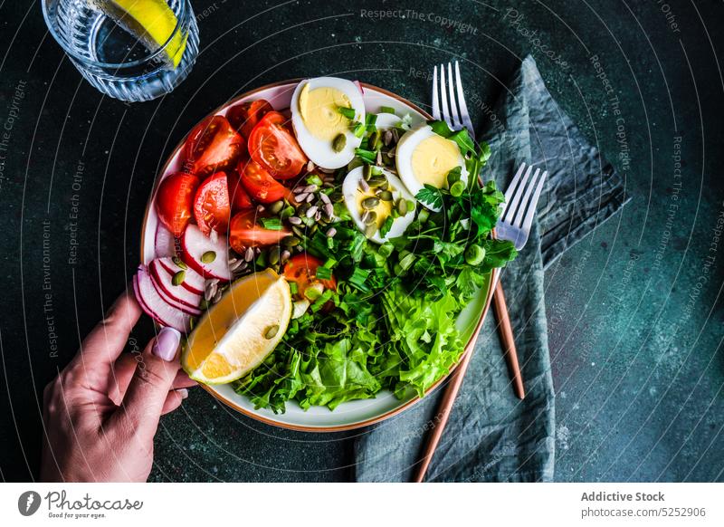 Anonymous person eating healthy raw vegetable salad boiled cutlery dinner egg food fresh glass hand herb hold lemon lettuce meal napkin organic bowl rocket seed
