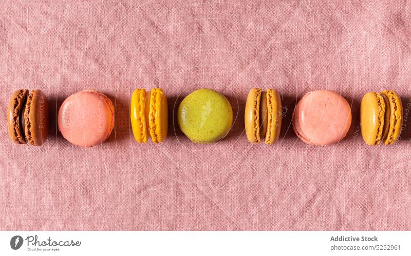 Colorful sweet macaroons on pink fabric dessert colorful row multicolored french confectionery tasty pastry line linen bright delicious tradition sugar