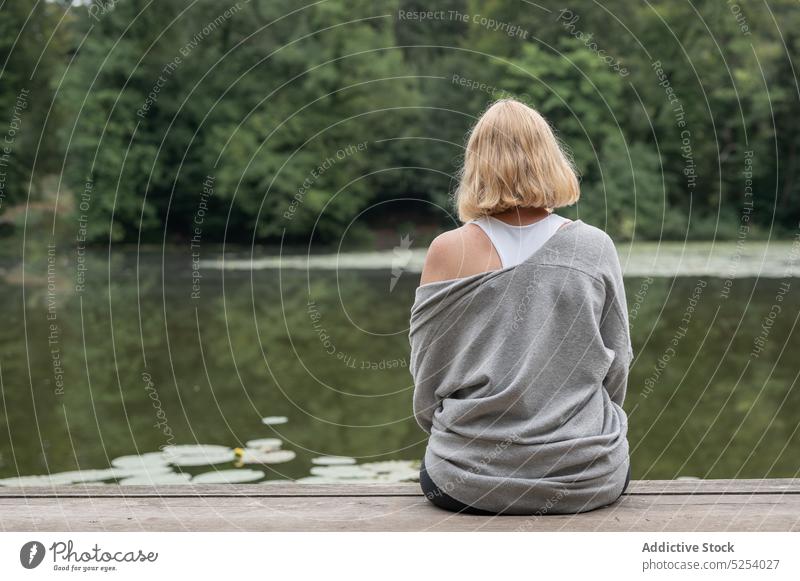 Woman sitting on pier near pond woman lotus leaf environment relax peaceful quiet harmony water nature middle age female enjoy lake pleasant calm greenery park
