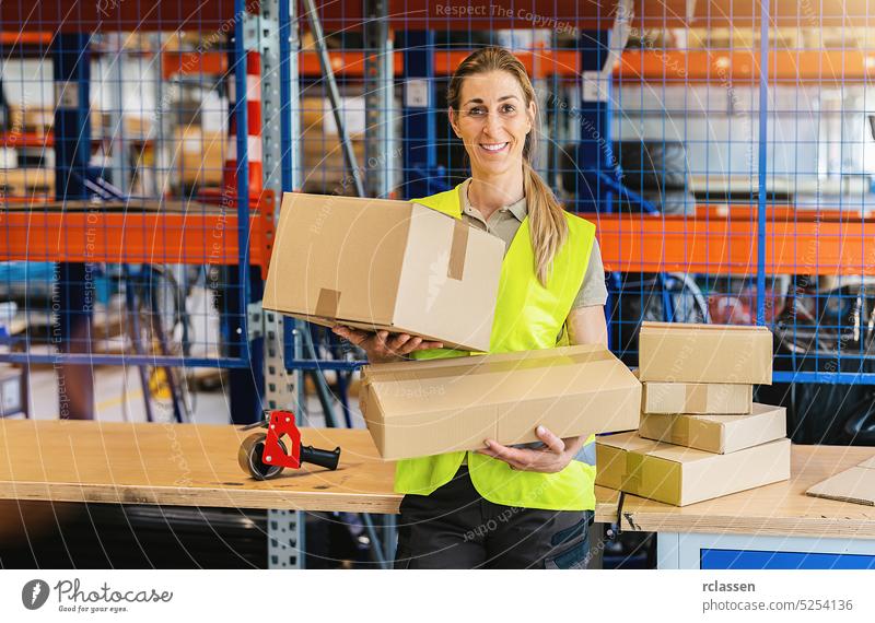 smiling female worker holding packing cases after sealing it with adhesive tape at warehouse of freight forwarding company box tape adhesive taping delivery
