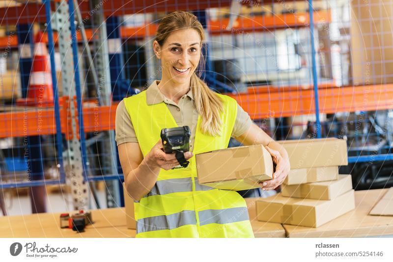 smiling female worker with protective vest and scanner, typing in package scanner, standing at warehouse of freight forwarding company box happy woman parcel
