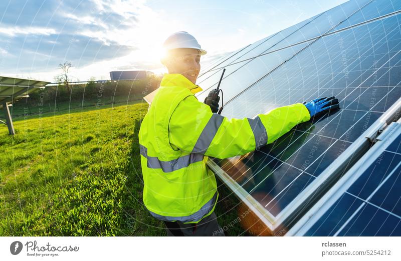 Female engineer talking in a walkie talkie to control or monitoring solar panels and smiling happy. Sustainable energy and solar power field concept image speak