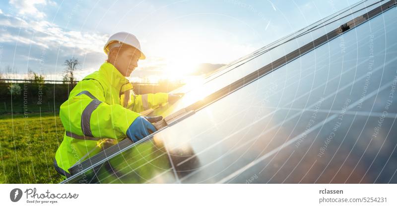 Female engineer mounting a solar panel in a solar field at sunset. Sustainable energy and solar power field concept image installer adjustment solar park