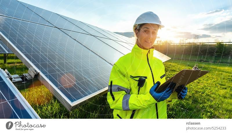 Female engineer looking away while monitoring solar panels and smiling happy. Sustainable energy and solar power field concept image business woman technology