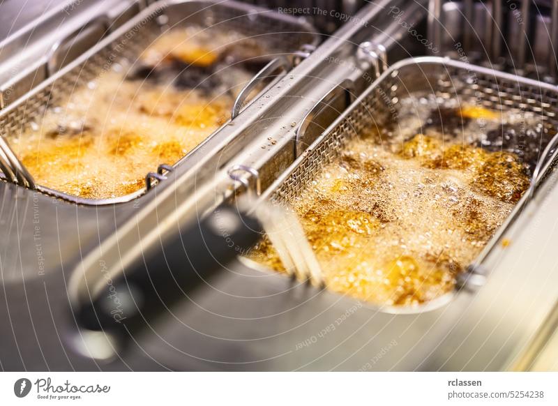 French fries cooking. Grid with strips hop potato lowered into boiling oil. Concept of fast food fryer deep professional restaurant kitchen machine oven