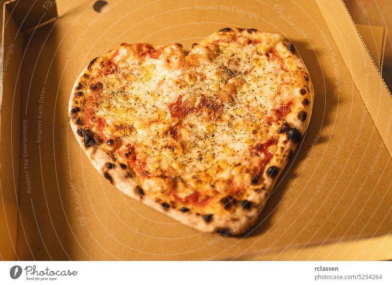 Fresh italian pizza in a heart shape from a stone oven in a box tuna italian pizzeria symbol sign smile love tasty cheesy salami delivery service happy