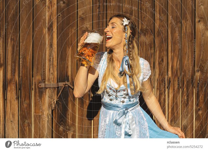 Woman at oktoberfest in traditional Bavarian Tracht drinking beer out of a huge mug in Bavarian or beer garden woman gold party restaurant alcohol beverage