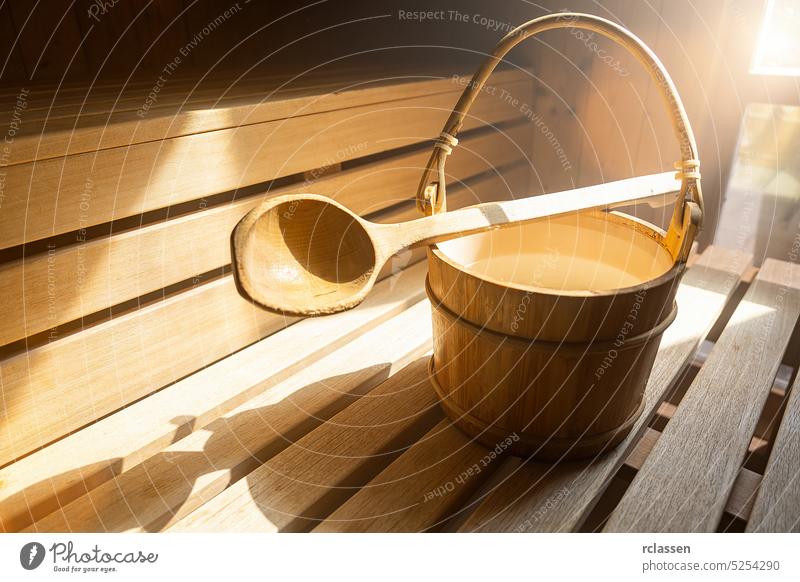wooden spoon with Water bucket with for pouring water on hot stones in the Finnish sauna, spa and Warm temperature bath therapy concept image. Sauna accessories in a sauna.