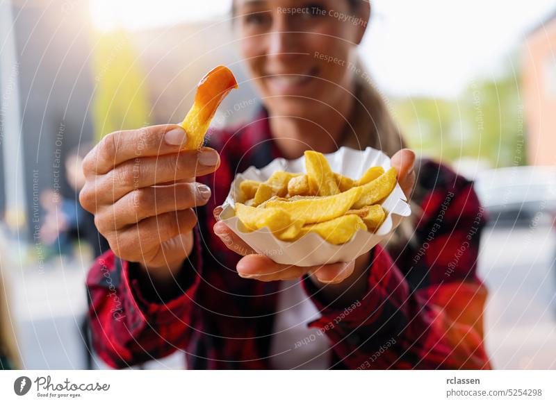 Woman eating French fries with ketchup German fast food outdoor in a street food cafe berlin currywurst junk food sausage bratwurst calories city diet fat