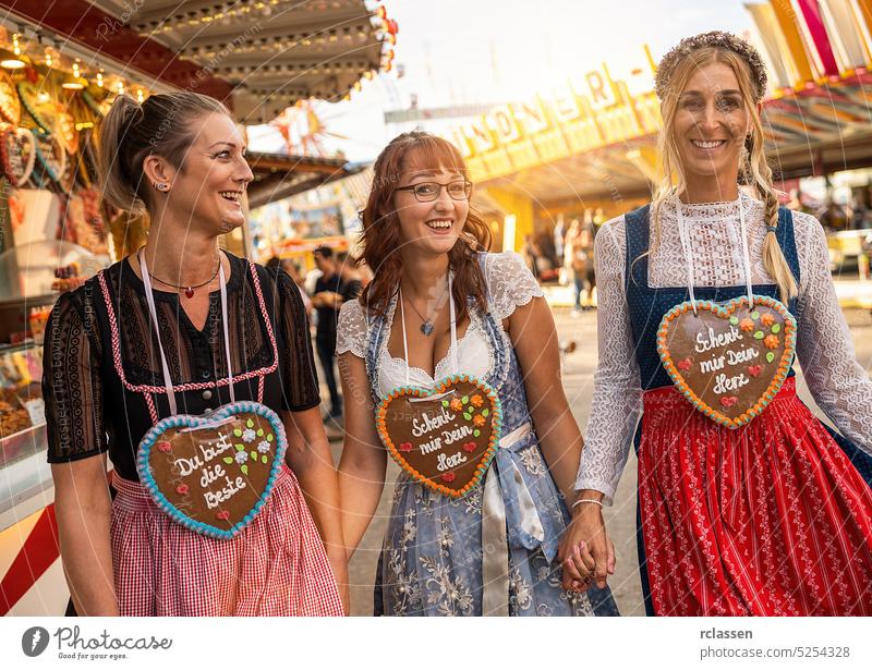 Girlfriends hafing fun at Bavarian fair or oktoberfest in Dirndl with Schenk mir dein Herz, Du bist die beste (German: Give me your heart, you are best ) written on gingerbreads heart