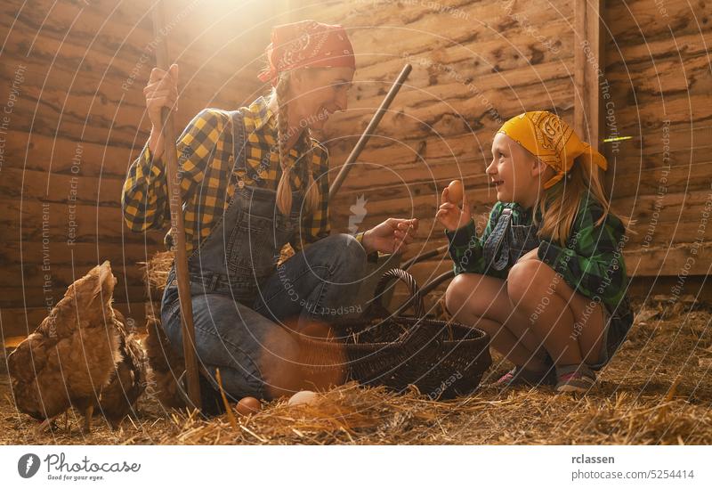 Proud chicken farmer woman and her daughter showing the organic eggs of her hens produced in a henhouse production child basket farming work person germany