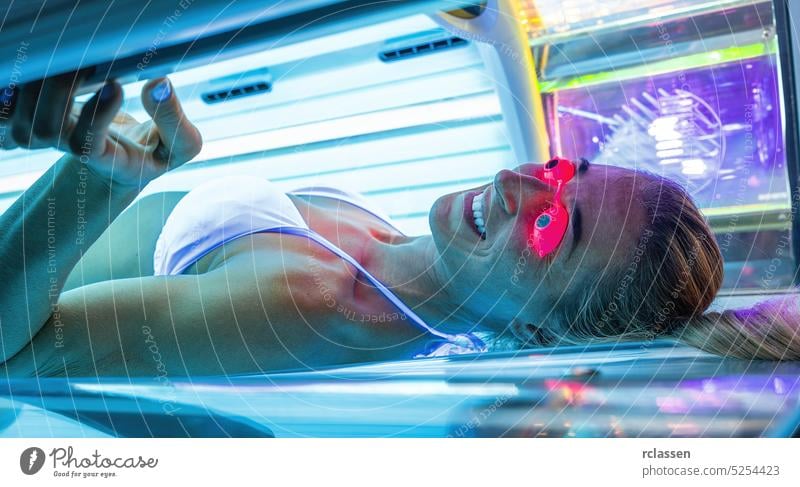 Attractive young woman tanning in solarium with glasses salon people light spa hair sun beauty face medicine lifestyle cosmetics skin sexy person modern
