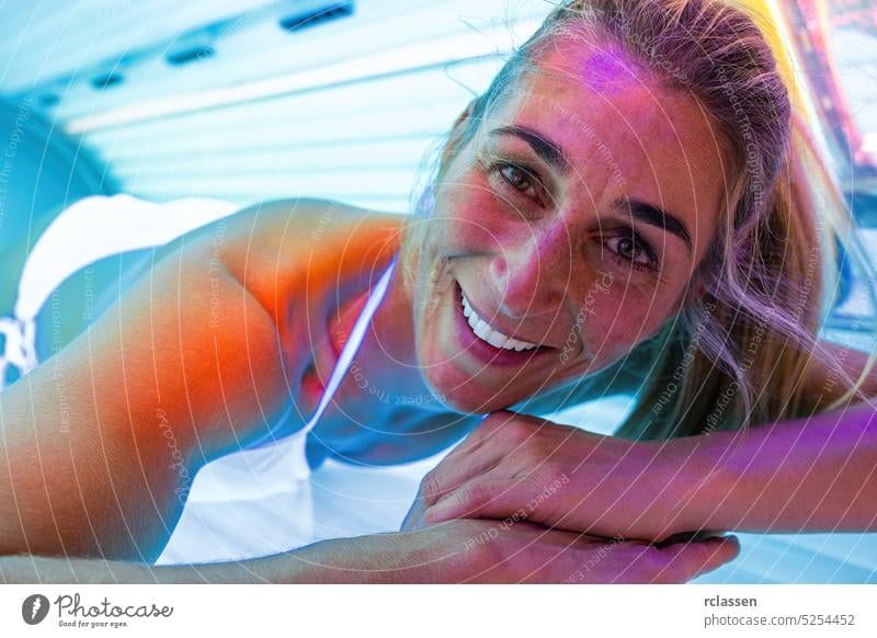 happy woman getting a tan in solarium and smiling bed tanning sunbathing salon people summer spring light spa girl health beauty lifestyle sunglasses cosmetics