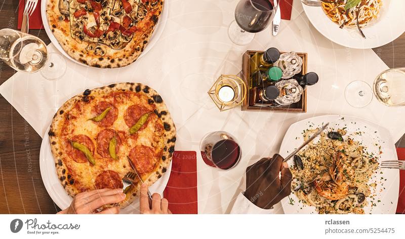 friends eating pasta, pizza and wine - people having meal in restaurant - Focus on center table - Summer lifestyle, food and friendship concept fish salami