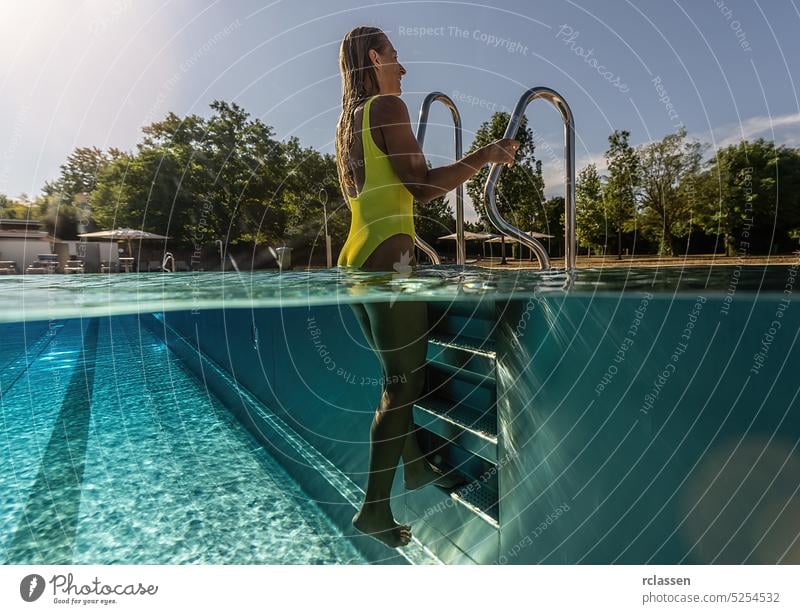 young woman stands by a ladder in a swimming pool, Split above and underwater photo handrails half split thermal resort splash smiling fashion beautiful
