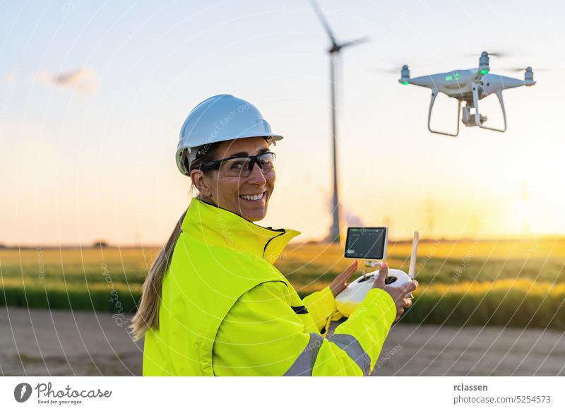 Happy Female Operator inspecting Wind turbine with drone at sunset. Drone inspection concept image. renewable energy wind park in europe smile happy aerial aero
