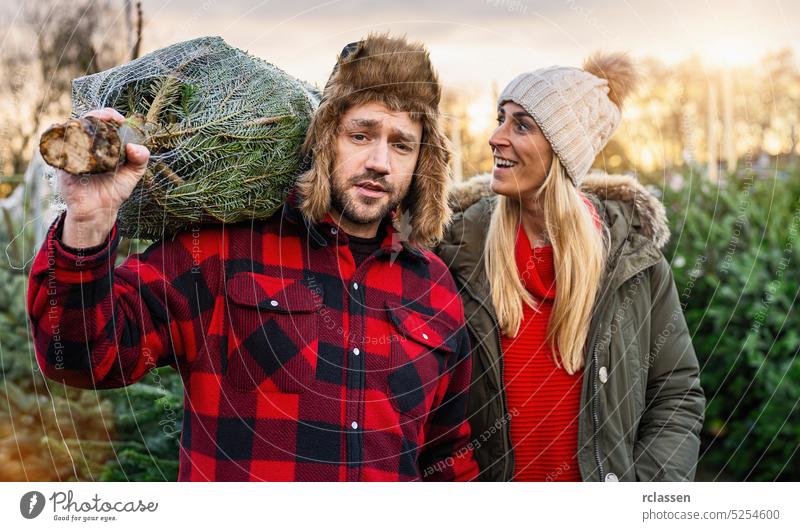 Man and Woman having bought a Christmas Tree carrying it home pine tree christmas woman people love winter girl sale couple smile cute lifestyle model xmas