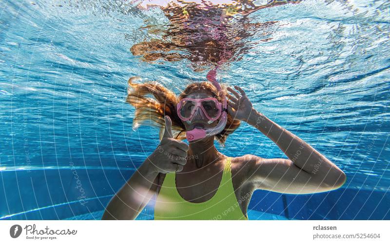woman in snorkeling mask dive underwater in swimming pool with thumbs up. Travel lifestyle, water sport outdoor adventure, swimming lessons on summer holidays.