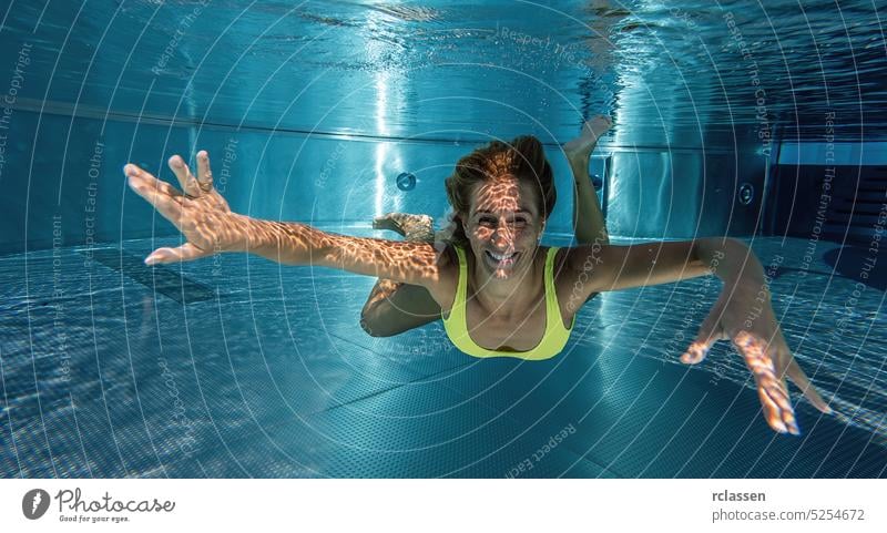 Young lady swimming underwater in the pool thermal resort splash smiling woman fashion beautiful young girl hair dive happy holiday people summer nature fitness