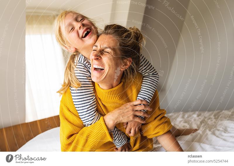 girl and her mother enjoy playing in the bedroom. Good time at home. Family playing on the bed in the bedroom. piggybacking mom family daughter happy mother kid