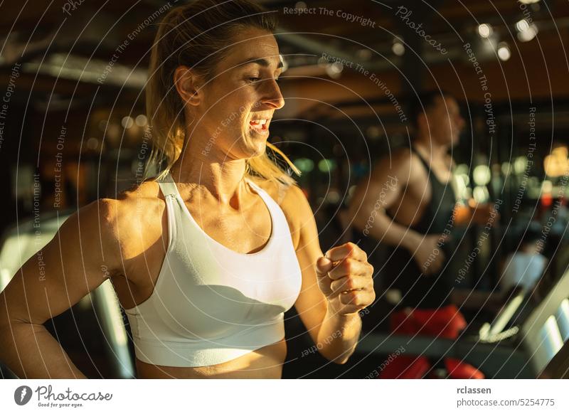 Side view of fit young woman and man while running side by side on modern electric treadmills at the gym lifestyle machine sportswear athletic fitness training