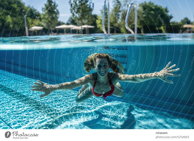 Split above and underwater photo of a woman swimming in pool during summer vacation in a hotel ladder handrails half split thermal resort splash smiling fashion