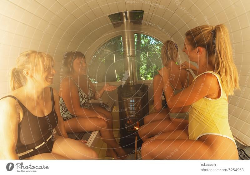 group of girls sitting in bathing suit in a hot wooden barrel sauna at in norway. Are relaxed and enjoy the holiday while relaxing in the finnish sauna cabin.
