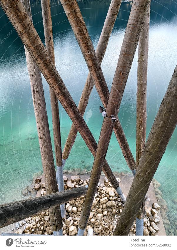 The wooden beams of an observation tower on the lake. The water is clear and cold. Below are many stones lying around Lake Water Calm Lakeside Colour photo Wet
