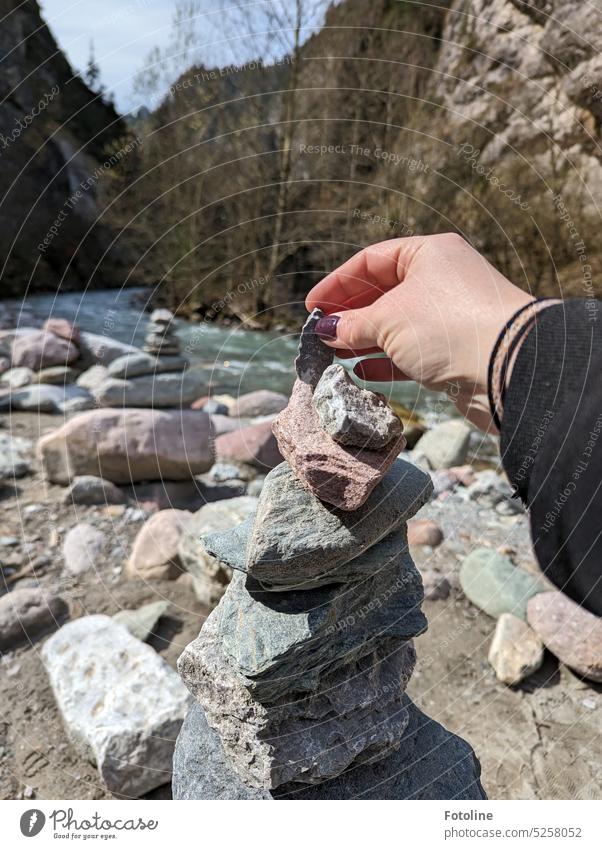 Stone on stone, that's how small cairns grow here in the Kundlerklamm gorge in Austria. The little towers are framed by high mountains. Pebble pebble spires