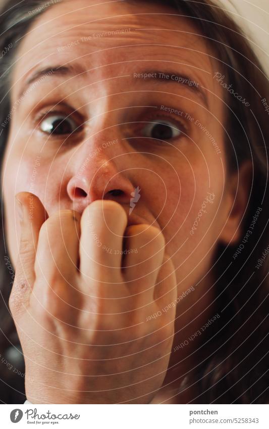 a woman looks frightened, fearful, holds her hand in front of her mouth and bites her fingers Fear Panic Gestures facial expression opened eyes Woman Face