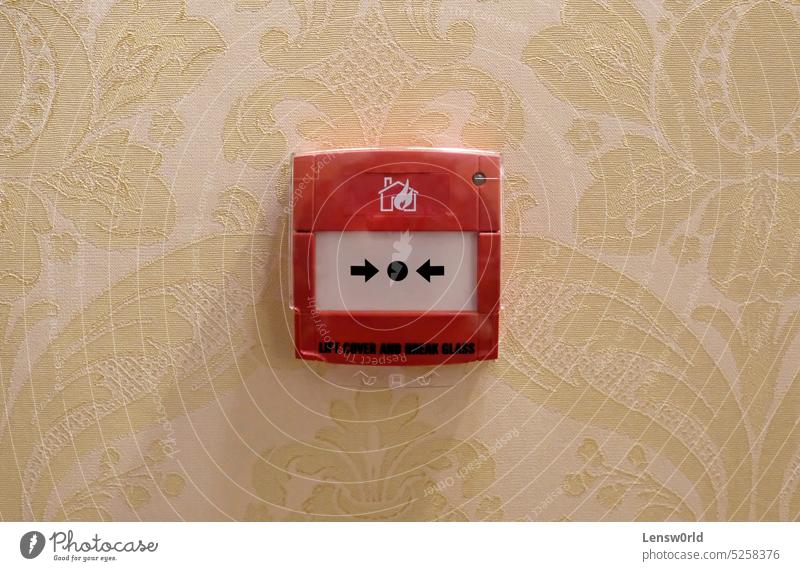 Fire alarm mounted on a wall in a hotel alert box break button danger emergency fire protection pull push red safe safety security sign symbol system warning