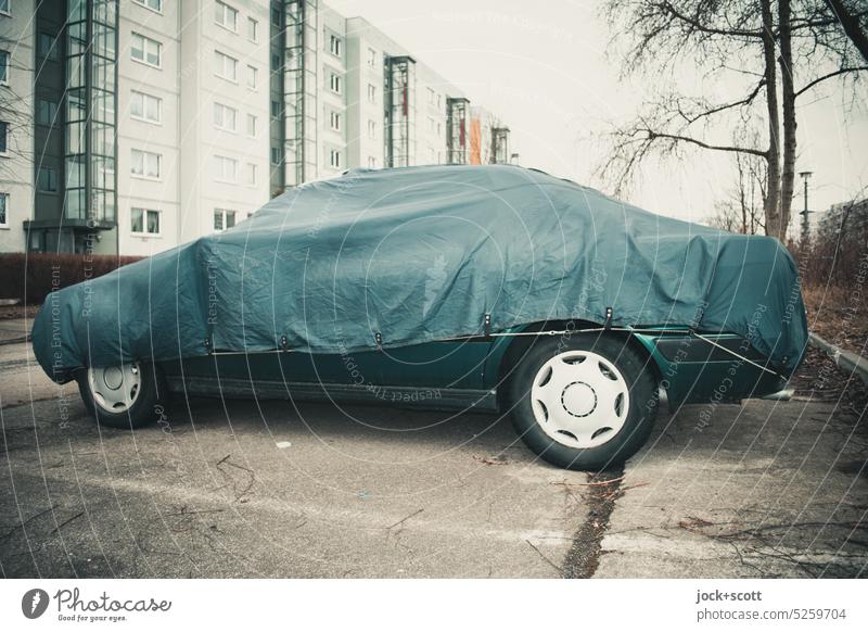a car parked winterized in front of the panel building Prefab construction Facade tarpaulin Car Parking Vehicle protection blanket Parking lot Protective cover