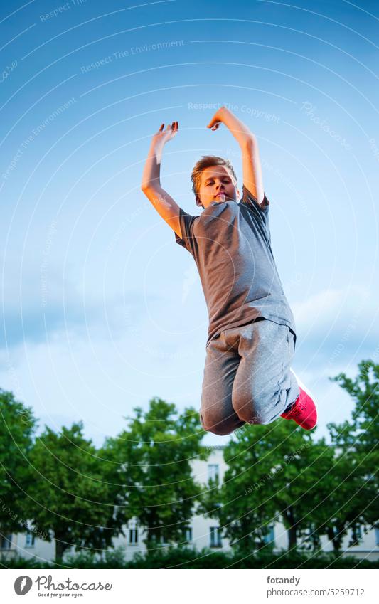 Boy jumping high Sprung springen aktiv allein Aussenaufnahme Luftsprung Bewegung Blick in die Kamera im Freien Freude fit Fitness sportlich Froschperspektive