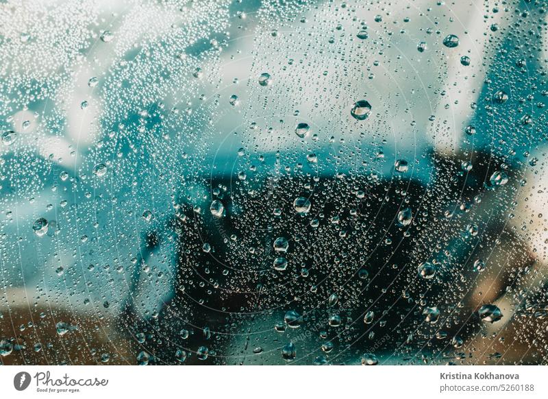 View of water drops falling on glass. Rain running down on window. Rainy season, autumn. Raindrops trickle down, blue sky. rain background liquid pattern