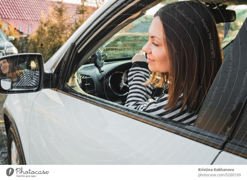 Happy woman driving white car, lady smiling, looking to mirror. Successful girl in automobile. female vehicle driver adult beautiful happy transportation young