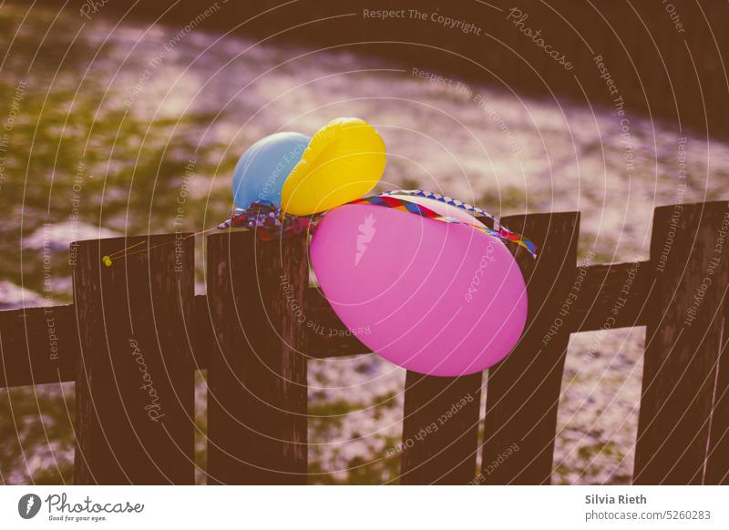 colorful balloons attached to a wooden fence - a Royalty Free