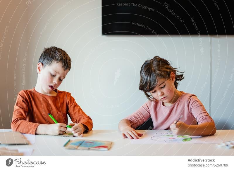 Siblings drawing environmental posters together sibling lesson school ecology focus paper boy girl brother sister children pupil creative childhood education