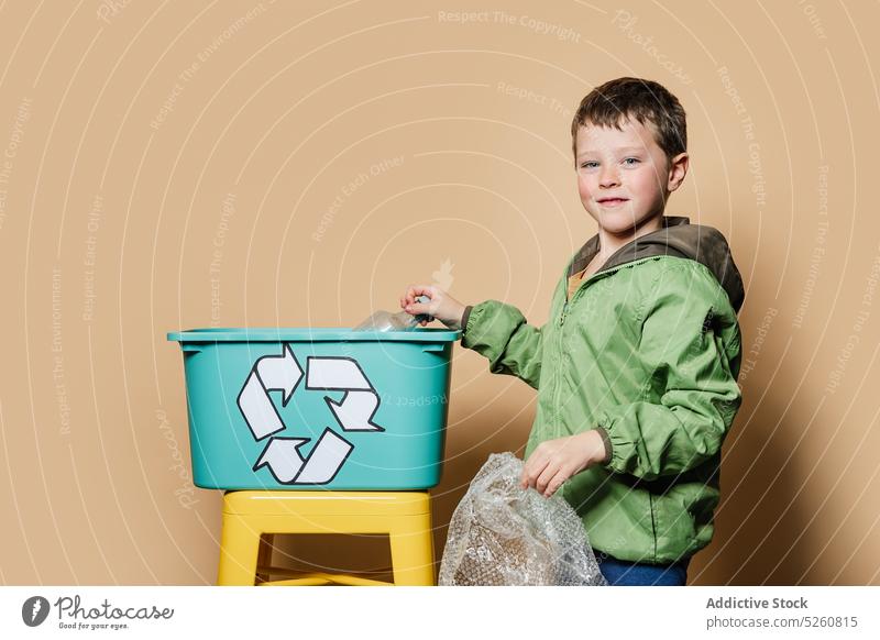 Boy putting litter in recycling box boy recycle smile save activist sort plastic environment kid package bottle wrapper garbage cheerful volunteer casual