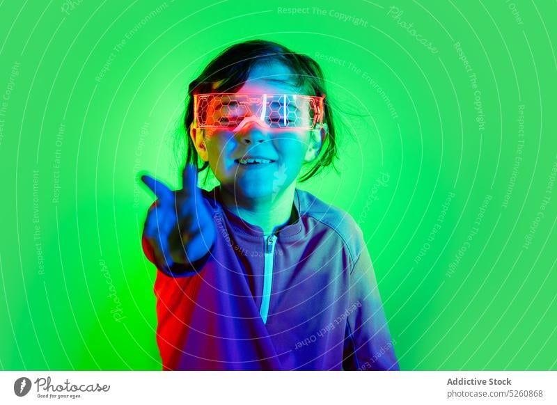 Funny girl in smart goggles touching invisible object kid air vr play game futuristic funny virtual reality projector neon hi tech child experience connection