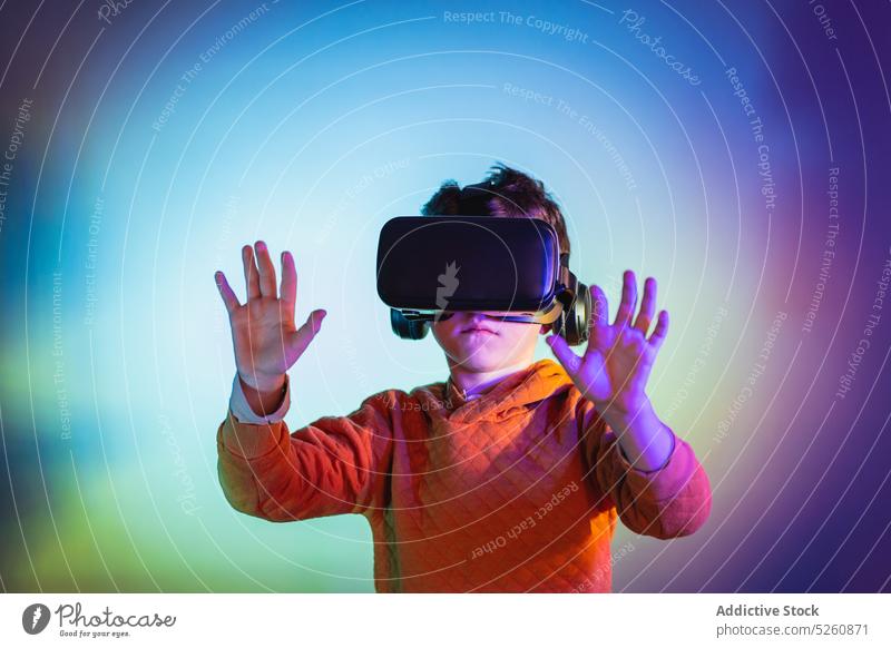Boy experiencing VR headset game on colorful background kid boy touch invisible object vr goggles futuristic cyberspace child connection entertain technology