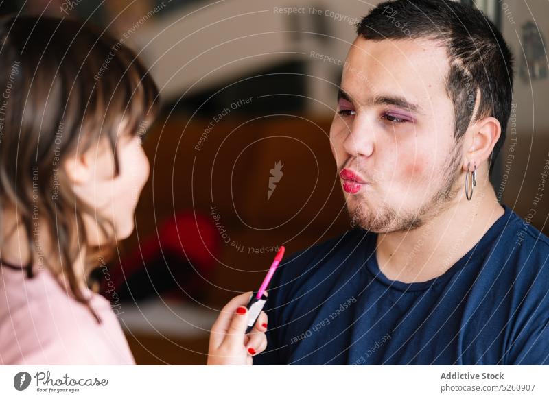 Cheerful girl applying lipstick on man father daughter play makeup having fun at home together bonding childhood positive kid cosmetic parent enjoy relationship