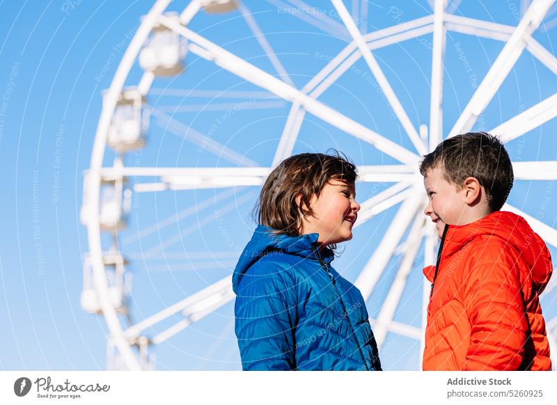 Cheerful brother and sister near Ferris wheel sibling children ferris wheel amusement park blue sky smile happy together fairground donostia san sebastian spain