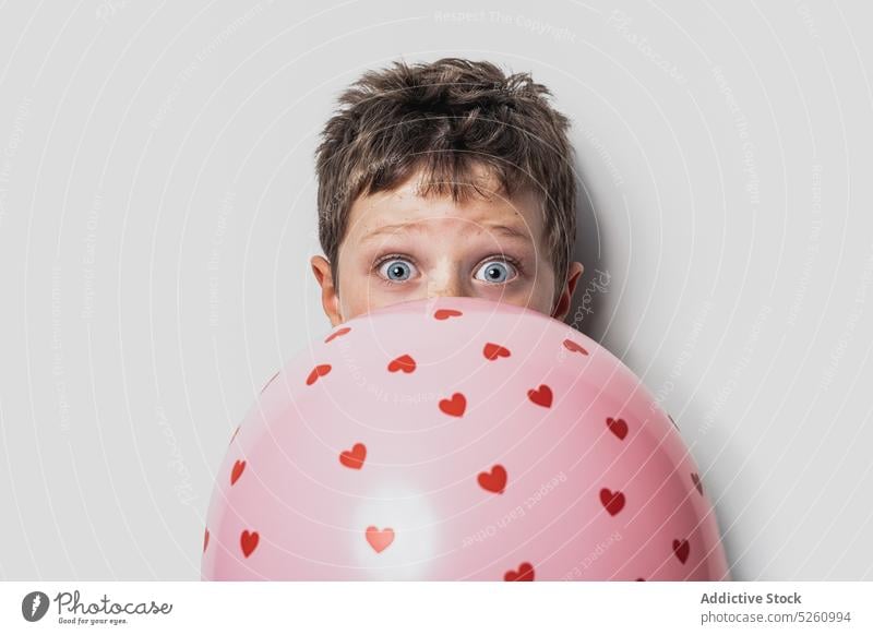Boy hiding face behind balloon boy cover face heart love hide saint valentine day holiday cute symbol child adorable occasion surprise kid romantic festive