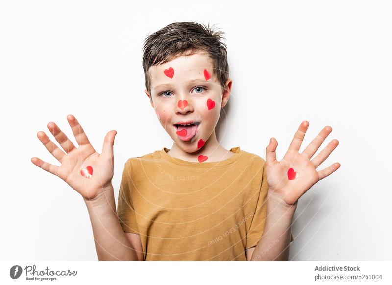 Boy with paper hearts showing hands and tongue boy show tongue cute love grimace funny symbol tongue out childhood playful adorable kid cheerful palm positive