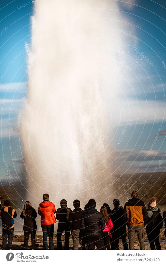 Geyser in action spewing hot water people admire geyser energy power traveler tourism nature iceland europe outerwear explore idyllic adventure geothermal