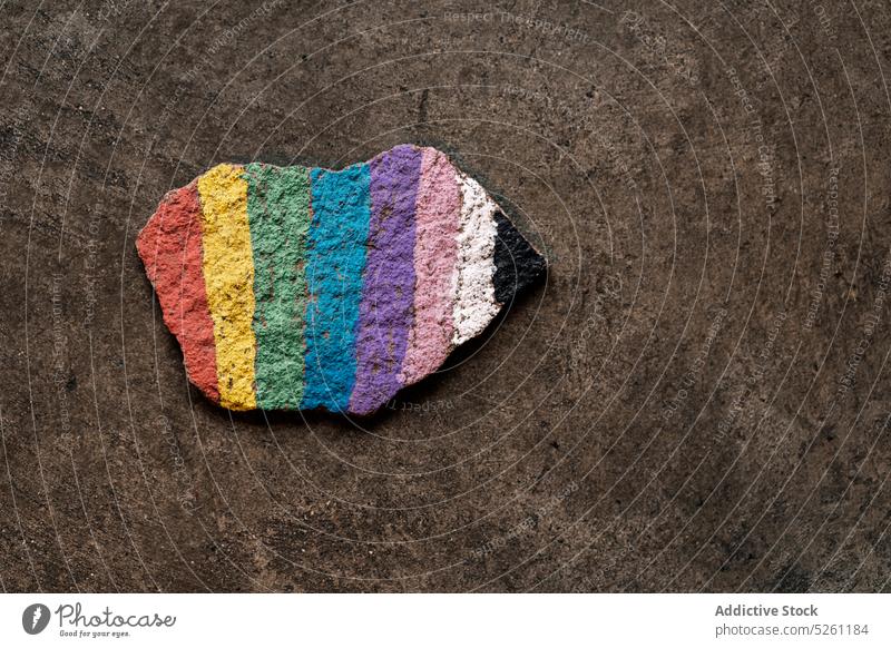 Rainbow colored piece of stone placed on gray background rainbow lgbt paint flag symbol pride colorful equal concept gay tolerance homosexual lesbian art lgbtq