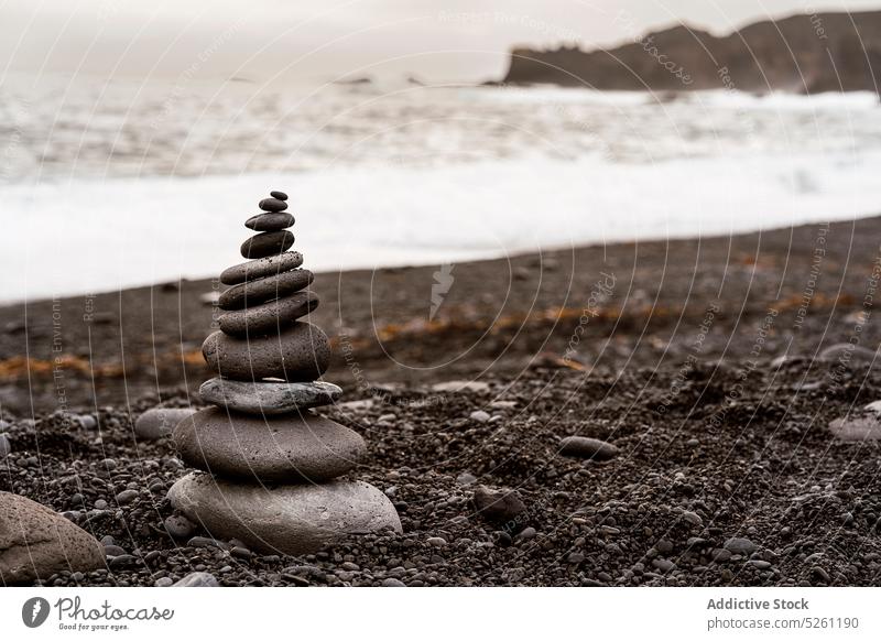 Stack of balancing rock on seashore on overcast day stone ocean beach volcanic nature landscape sand balance zen formation stack scenic sky picturesque rough