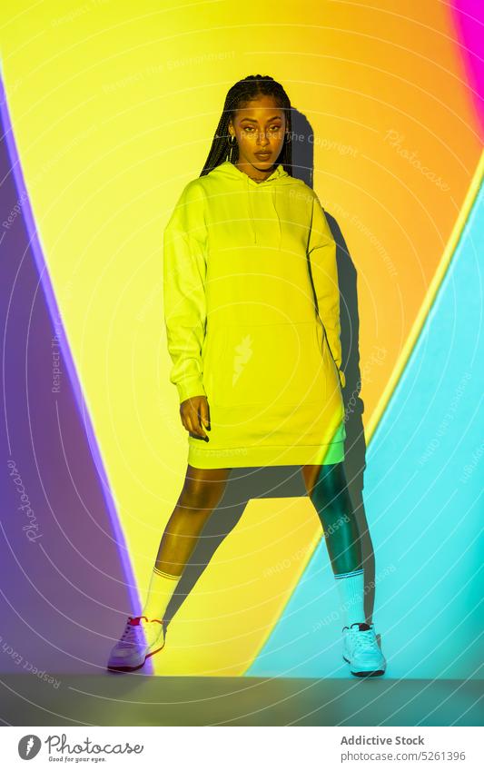 Young black female standing in studio against yellow and blue lights woman model geometry neon effect luminous glow line studio shot african american ethnic