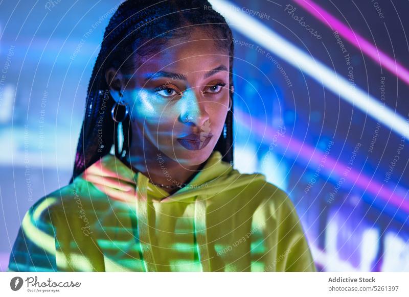 Black female standing in studio with neon lights woman model portrait multicolored effect projector confident studio shot african american black ethnic young
