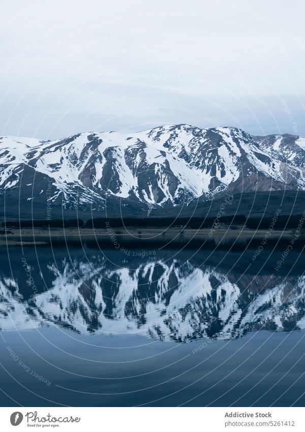 Snowy mountains near clear lake snow landscape water nature overcast reflection highland picturesque scenic winter environment range calm tranquil cold scenery